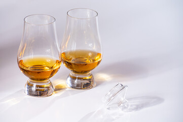 Tulip-shaped tasting glasses with dram of Scotch single malt or blended whisky on white background