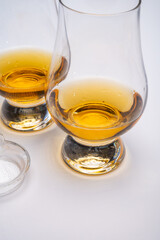 Tulip-shaped tasting glass with dram of Scotch single malt or blended whisky on white background