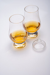Tulip-shaped tasting glass with dram of Scotch single malt or blended whisky on white background