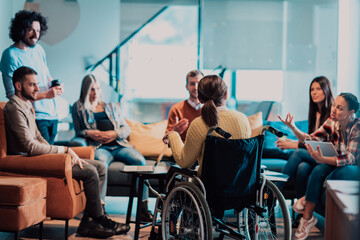Obraz premium Businesswoman in wheelchair having business meeting with team at modern office. A group of young freelancers agree on new online business projects