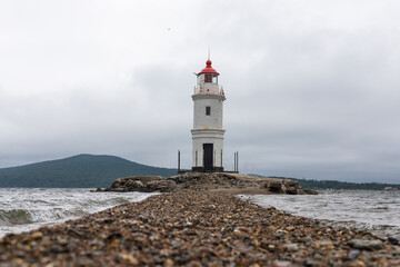 Fototapeta na wymiar Tokarevsky Lighthouse (Egersheld Lighthouse or Tokarevskaya Koshka lighthouse) on a cloudy summer day. Vladivostok, Russia. Lighthouse on the seashore,seascape