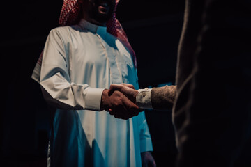An elderly Arab man shaking hands with a businessman and ending a business meeting with successful business deals