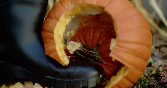 Halloween jack-o'-lantern being smashed by a black boot. Close-up framing shot in slow motion.