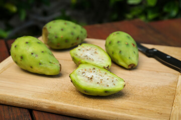 Tasty prickly pear fruits on wooden table, closeup