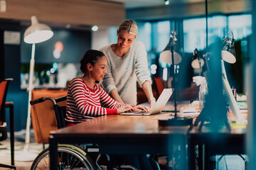 Businesswoman in a wheelchair working in a creative office. Business team in modern coworking...
