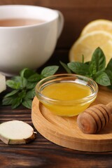 Bowl with honey for tea, lemon, mint and ginger on wooden table