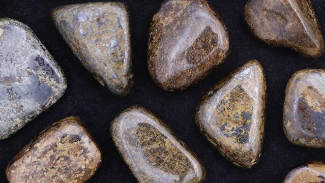 Bronzite rare jewel stones texture on black background. Moving right seamless loop backdrop.