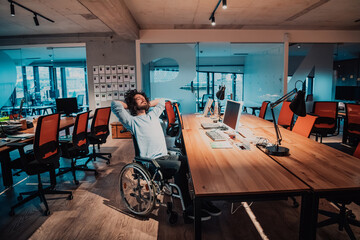 Fototapeta na wymiar Businessman with a disability in wheelchair working overtime alone at his desk in an office late at night