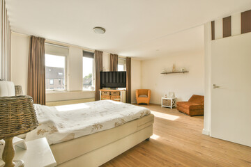 Comfortable bed located near glowing lamp and armchair in contemporary bedroom with small window...