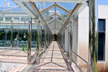 The Tiled corridor under a glass roof of a modern building with abstract design in Thailand.