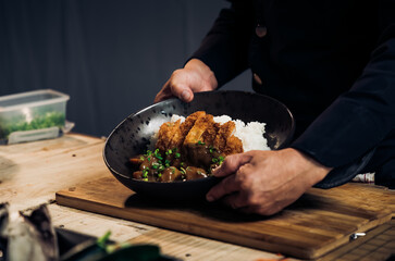 Japanese chicken katsu curry rice, deep fried breast chicken fillet with beef, carrot and potato curry in black plate on wooden table Crispy fried pork cutlet with curry rice  - Japanese food style