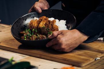 Japanese chicken katsu curry rice, deep fried breast chicken fillet with beef, carrot and potato curry in black plate on wooden table Crispy fried pork cutlet with curry rice  - Japanese food style
