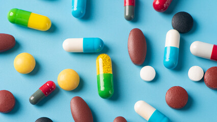 multicolored pills and capsules on blue background as Medical concept. Concept of threat of various diseases. 