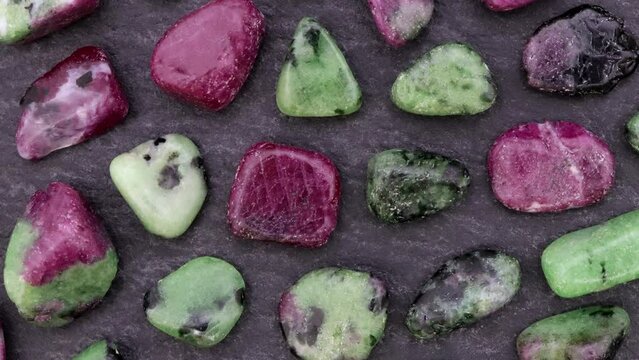 Ruby zoisite rare jewel stones texture on black stone background. Moving right seamless loop backdrop.
