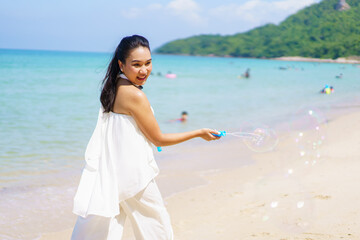 Fototapeta na wymiar Happy Asian woman enjoy playing with a soap bubble at the beach.