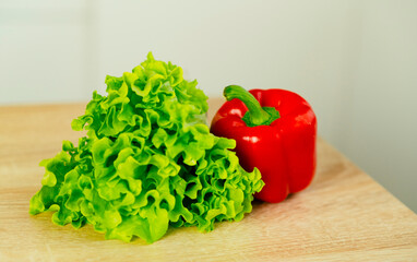 Bulgarian red pepper, green lettuce on table in kitchen. Fresh vegetables. Close up. Food concept. Health food.