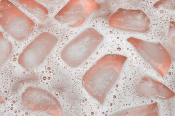 Ice cubes melting in pink liquid