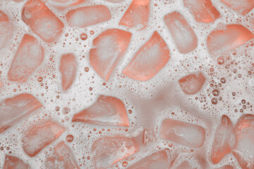 Ice cubes melting in pink liquid