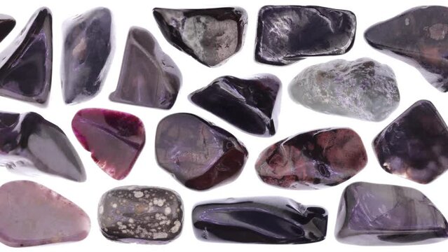 Sugilite jewel stones set texture on white isolated background. Macro closeup. Moving right seamless loop backdrop.