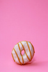 isolated mini donut with white glaze on pink background 