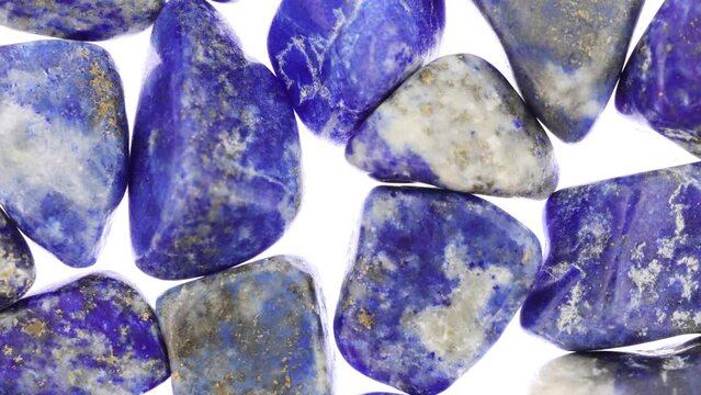 Lapis lazuli heap jewel stones texture on white light background. Moving right seamless loop backdrop.