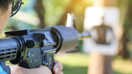 Air soft gun holding by man aiming at the blur shooting target in the shooting range, soft and selective focus on the gun                              