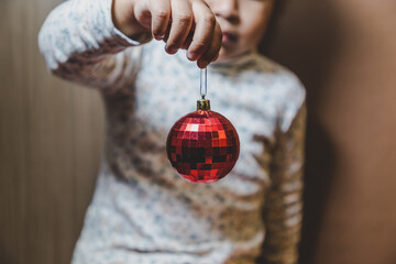 niña feliz y sonriente sosteniendo en sus manos objetos decorativos navideños, bolas o esferas...