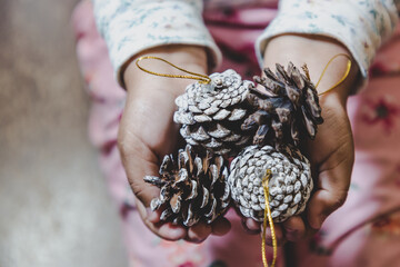 niña feliz y sonriente sosteniendo en sus manos objetos decorativos navideños, bolas o esferas...