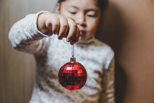 ni&ntilde;a feliz y sonriente sosteniendo en sus manos objetos decorativos navide&ntilde;os, bolas o esferas navide&ntilde;as  y letras de feliz navidad en ingles, concepto navidad, amor, paz y compartir. 
