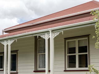 Cottage with red iron roof and white columns with brackets