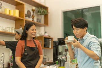 Female customer is happy to take a taste of fresh hot coffee from a young café owner. Lady with warm hospitality and care hands a cup of hot drink to her client