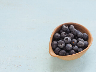 Fresh blueberries in oval brown plate on blue background. Flat lay with copy space. Concept for healthy eating and nutrition, Superfood..