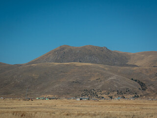 Mountains in the Midst of Dry and Yellow Soil in Contrast to a Beautiful Clear Blue Sky