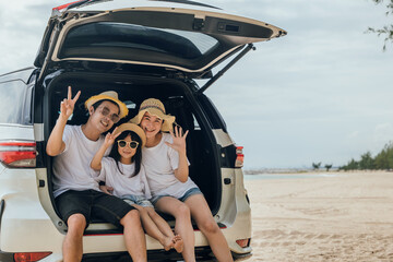 Fototapeta na wymiar Tourism Day. Family having fun in summer vacation on beach show V-sign finger. Parents and kid family travel in holiday at sea beach. Father, Mother and daughter enjoying road trip sitting on back car