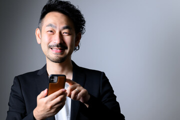 スマホを持って正面を向く髭の中年男性　カメラ目線