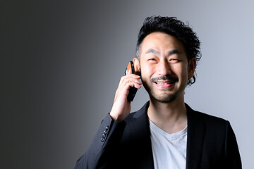 Middle-aged Asian man with beard facing forward holding a cell phone　