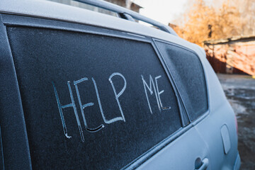The text Help Me on the frozen glass of the car