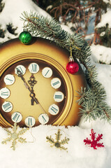 Antique clock, snow-covered spruce and Christmas decorations on a snowy background.