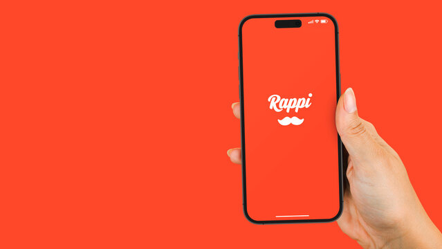 Female hand holding a smartphone iPhone 14 Pro with Rappi app on the screen. Orange background. Rio de Janeiro, RJ, Brazil. November 2022