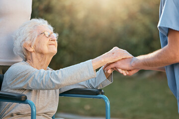 Elderly woman, wheelchair and caregiver holding hands for support, care and solidarity in nature park. Senior person, patient disability and healthcare nurse communication in retirement home outdoor