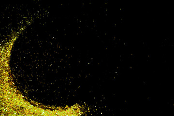 Gold glitter powder sparkling on black background.texture christmas