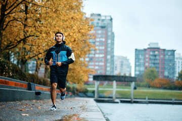 Fototapeta premium Motivated athletic man running outdoors during bad weather.
