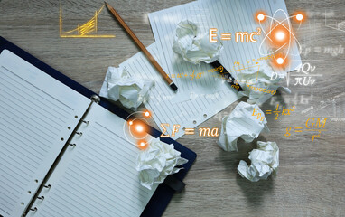 Notebooks and pencils and crumpled paper lay on the table with Albert Einstein and Isaac Newton's...