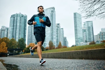 Poster Below view of male athlete jogging in rain. © Drazen