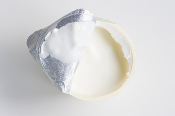 Top view of an open yogurt cup isolated on a white background. Plain full-fat sheep milk yogurt.
