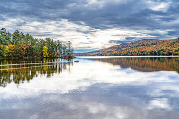 The cloudy sky is reflected in the Adirondack lake in the Fall in New York