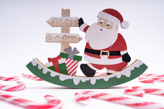 Santa Claus wooden decoration figurine on white background with inscription Merry Christmas and candy canes on the floor