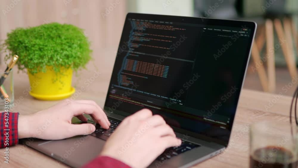 Wall mural close up of freelancer's hands typing code on laptop keyboard. camera slides around developer's fige