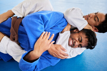 Men, martial arts and karate choke hold in dojo to practice fighting skill. Training, taekwondo and fitness class for self defense, workout or exercise challenge with people in match or competition.