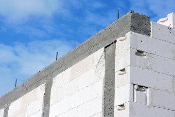 A reinforced concrete beam and reinforced concrete columns,  walls made of autoclaved aerated concrete blocks, blue sky in the background